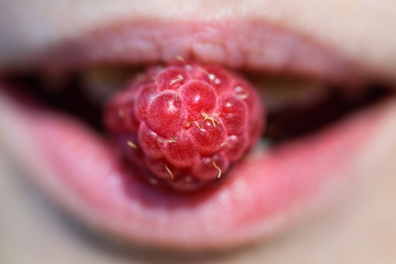 Girl with raspberries in her mouth